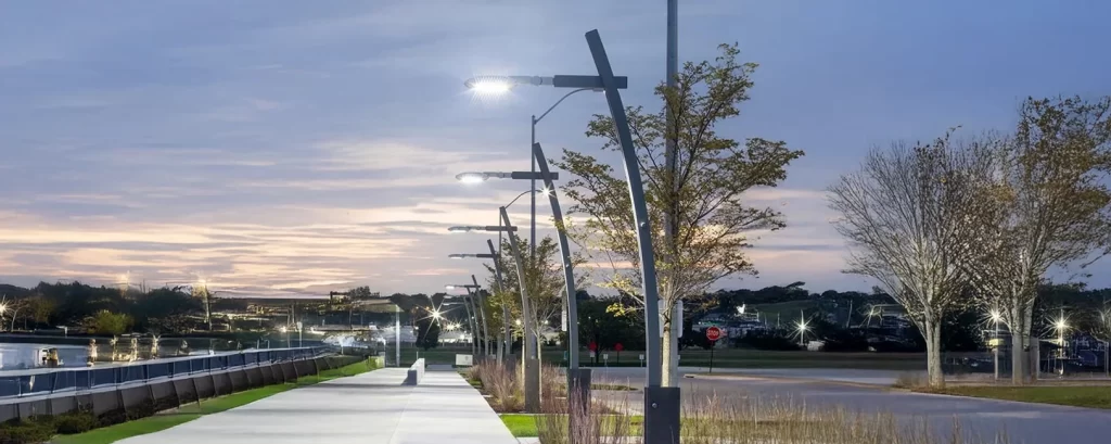 Rua urbana iluminada com postes LED modernos, promovendo segurança e economia.